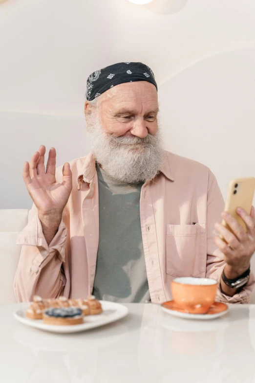 a bearded man sitting at a table with his cell phone