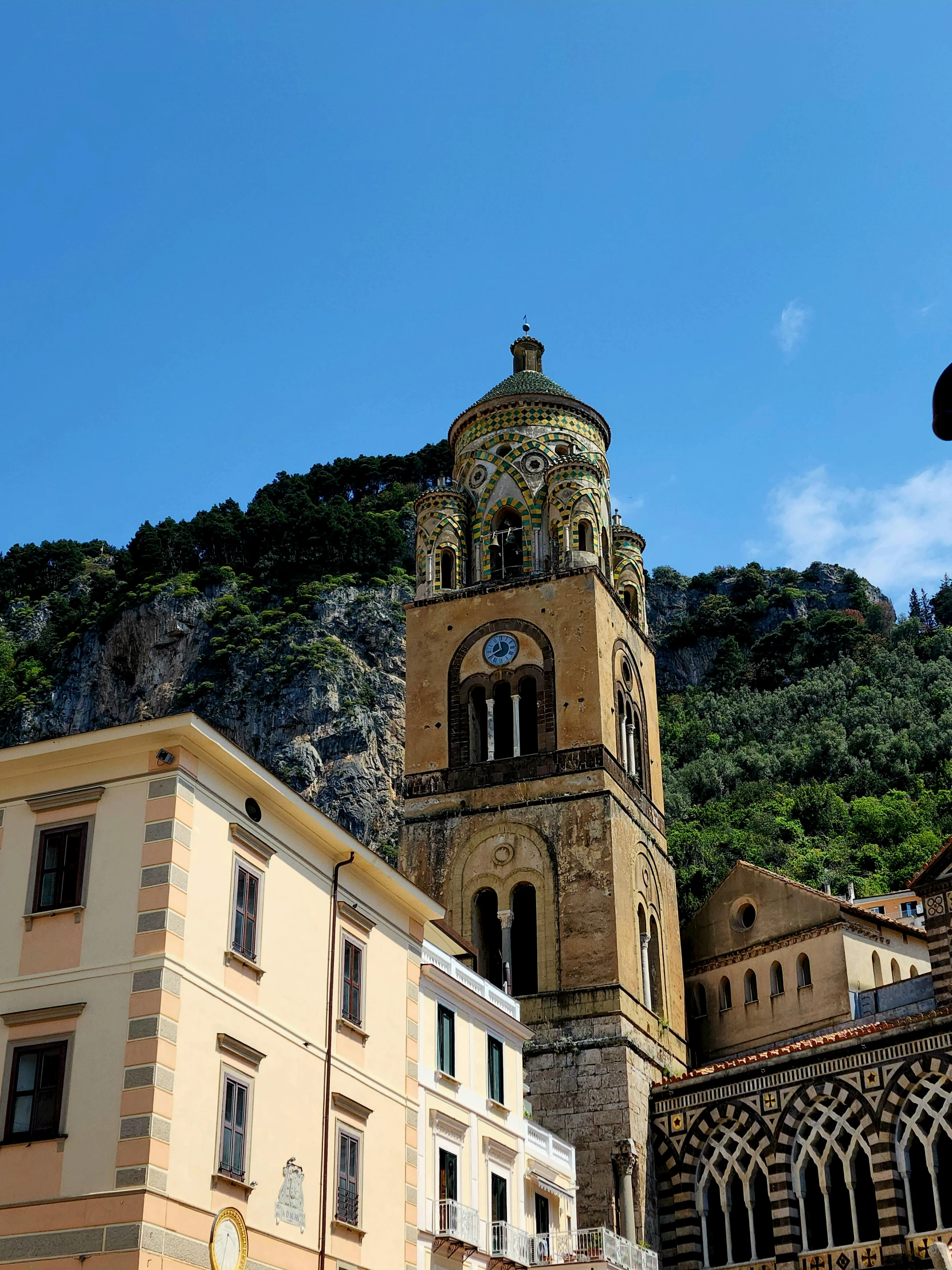 some buildings and a clock tower with a mountain behind them