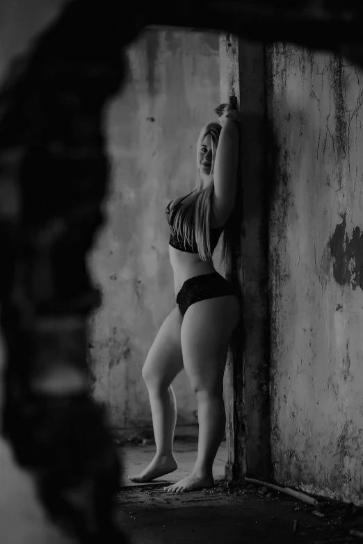 a girl in a  lingerie stands against a wall