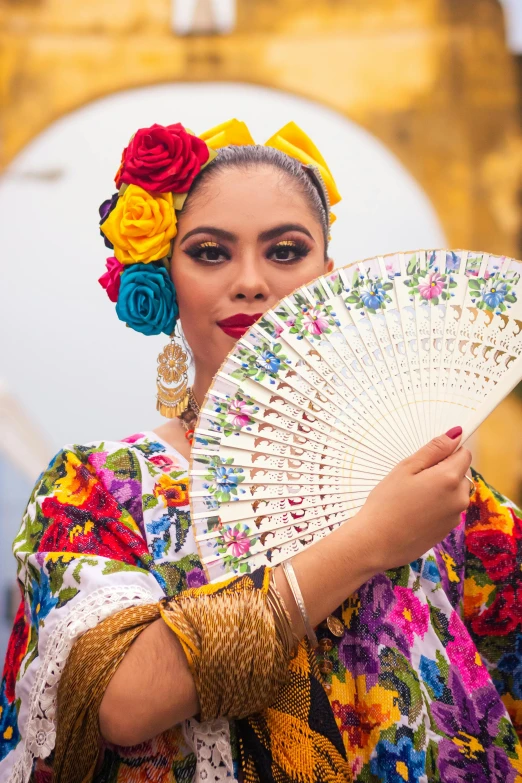 a woman dressed up and holding a white fan