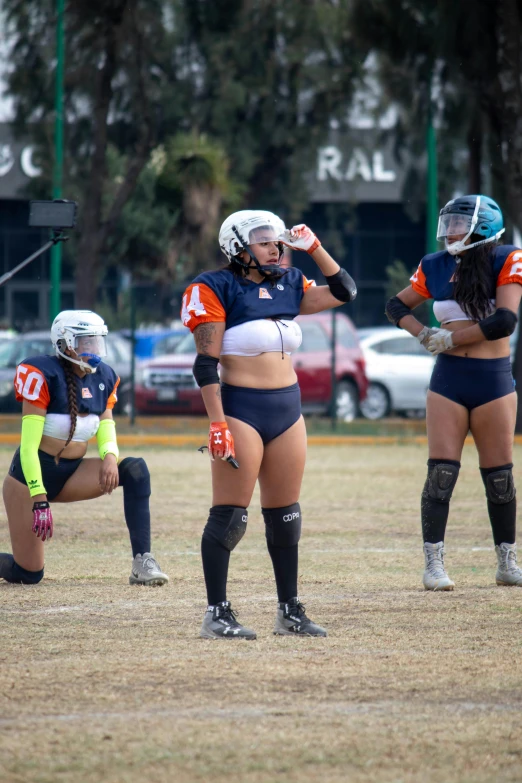 three women dressed in matching sports outfits stand on a field