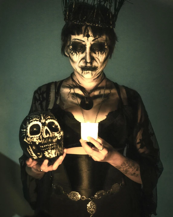 a woman dressed in makeup holding up a lit candle