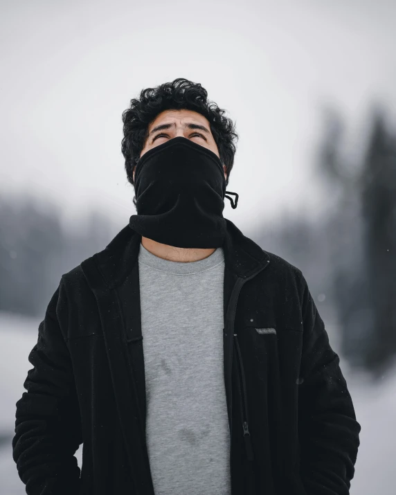 a man with a black face mask standing in the snow