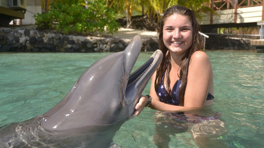 a young woman is holding the head of a dolphin