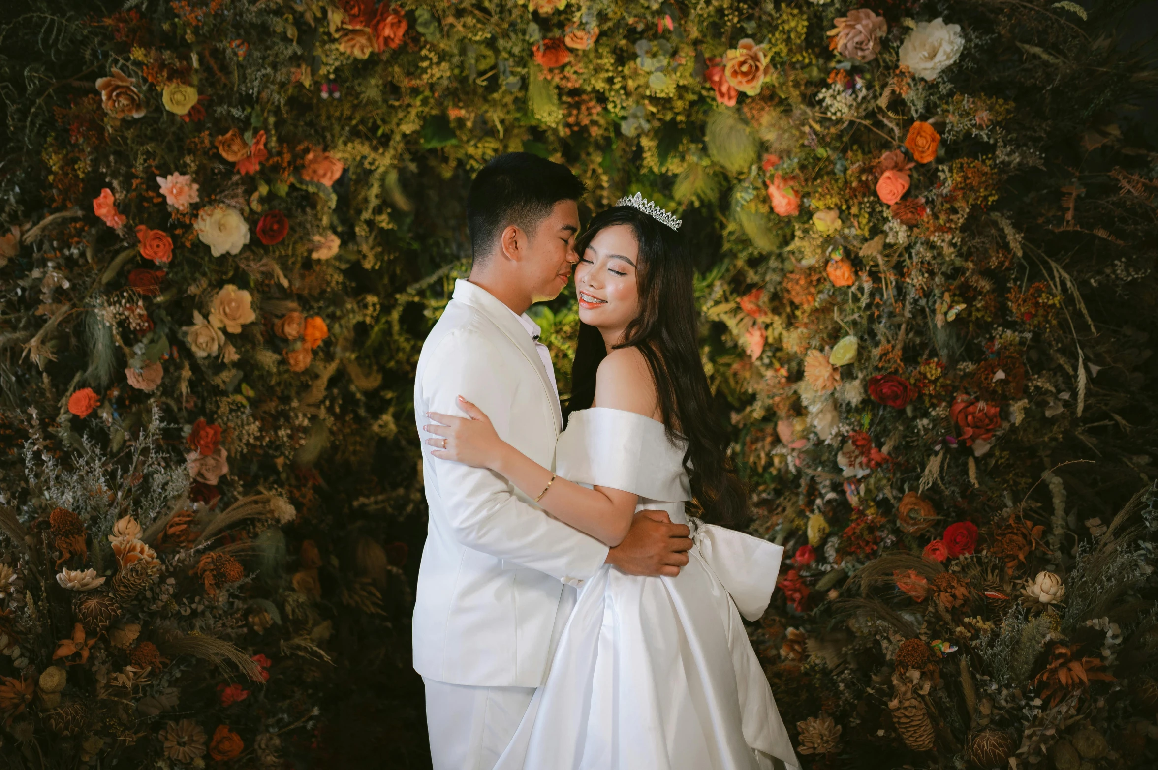 a couple is posing for a picture under the arch of flowers