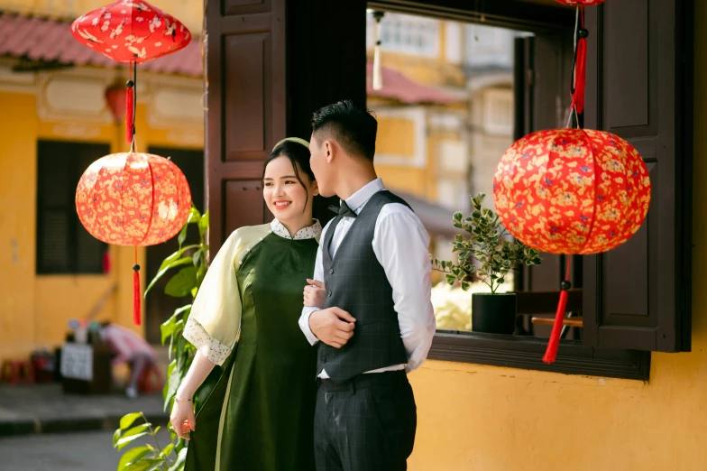 two asian people pose in front of a chinese building