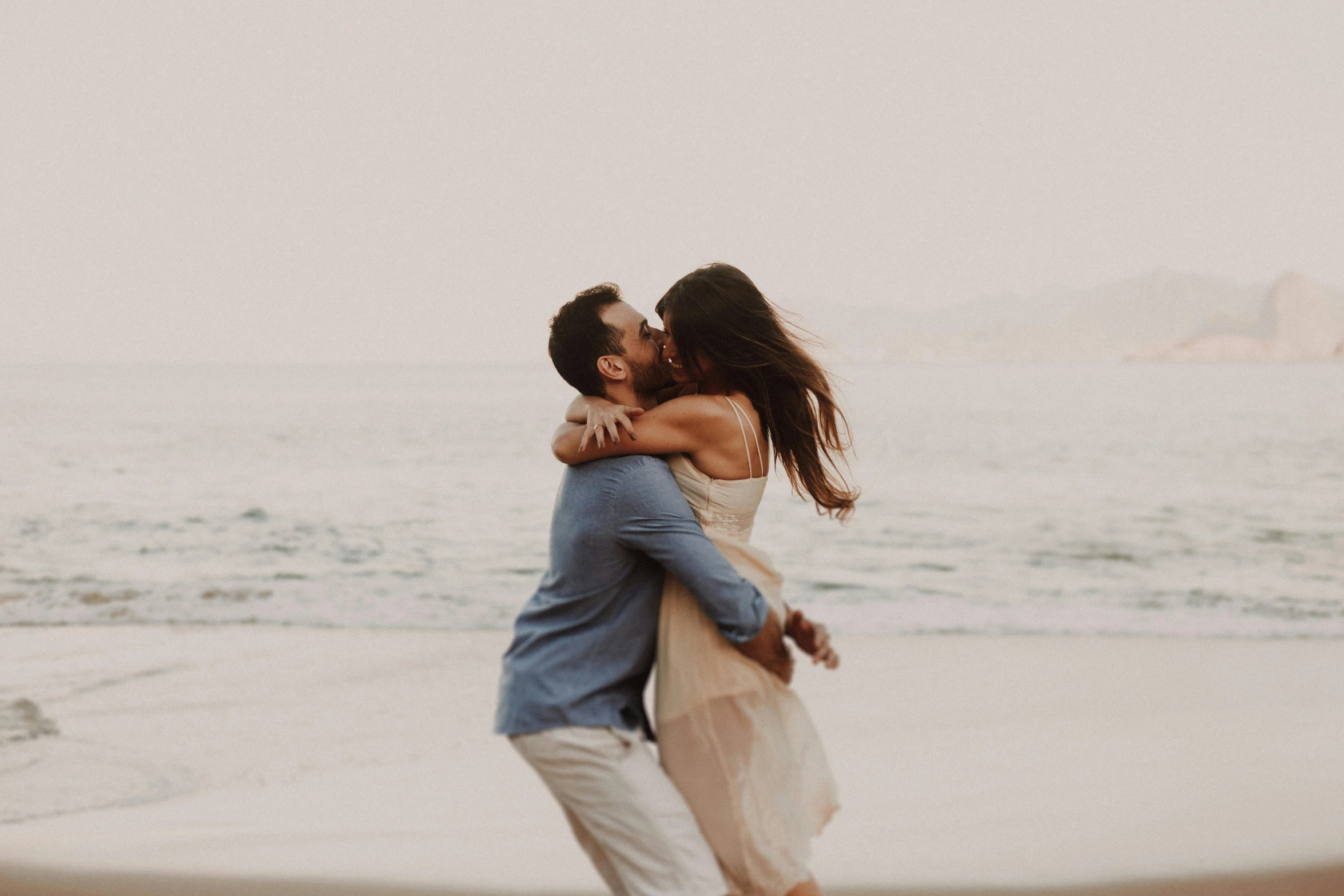 a couple emcing on the beach by the ocean