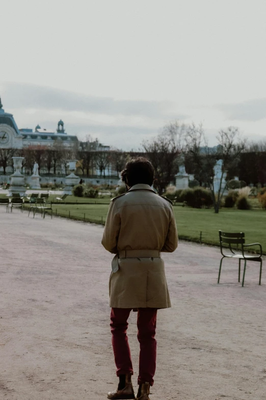 a person wearing a coat standing near a park