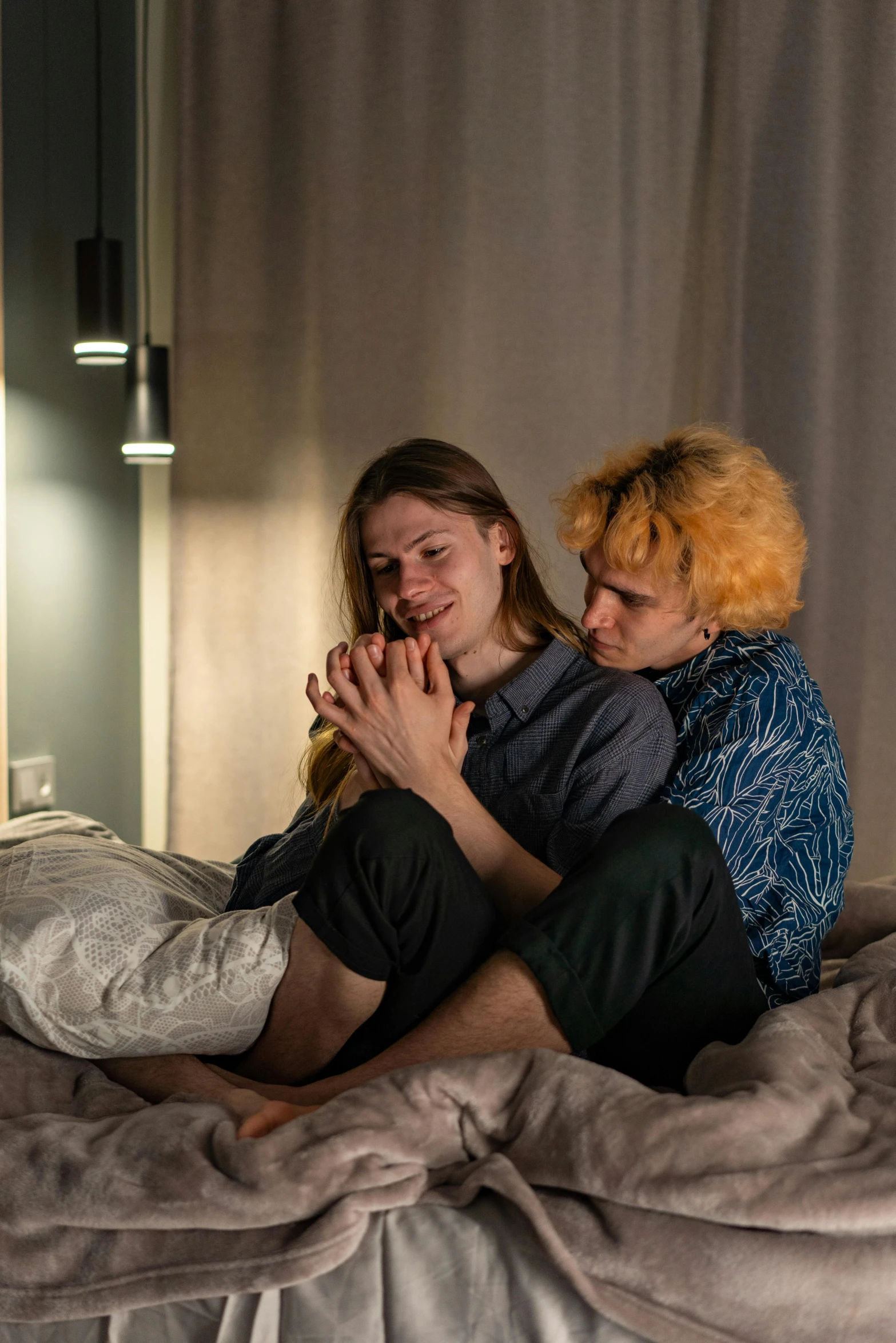 two woman on top of the bed with one looking at her phone