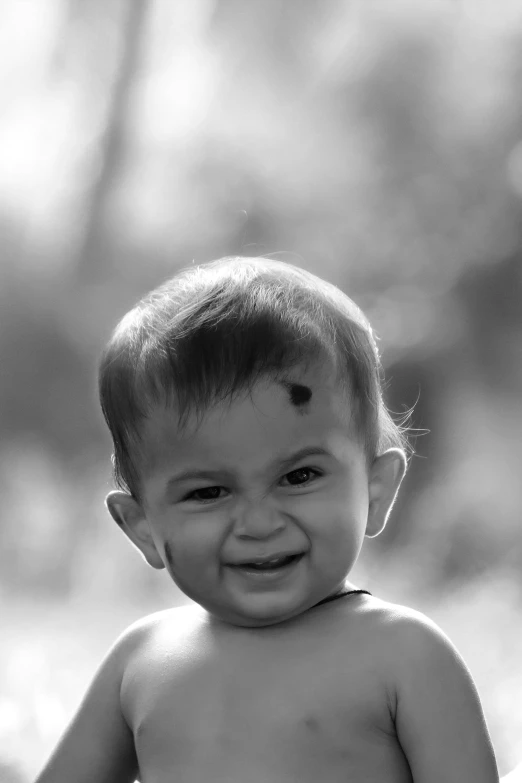 a young baby smiles at the camera while standing in a field