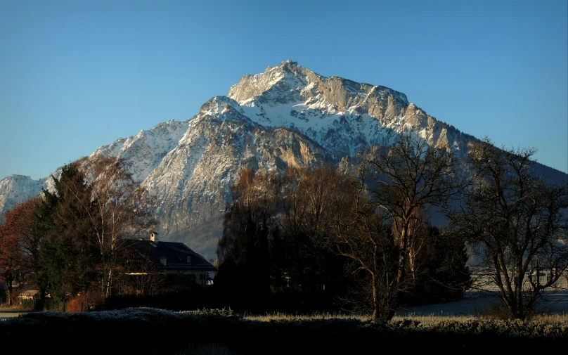 a large snow - covered mountain sits high over the woods