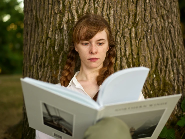 a woman reading on the ground by a tree