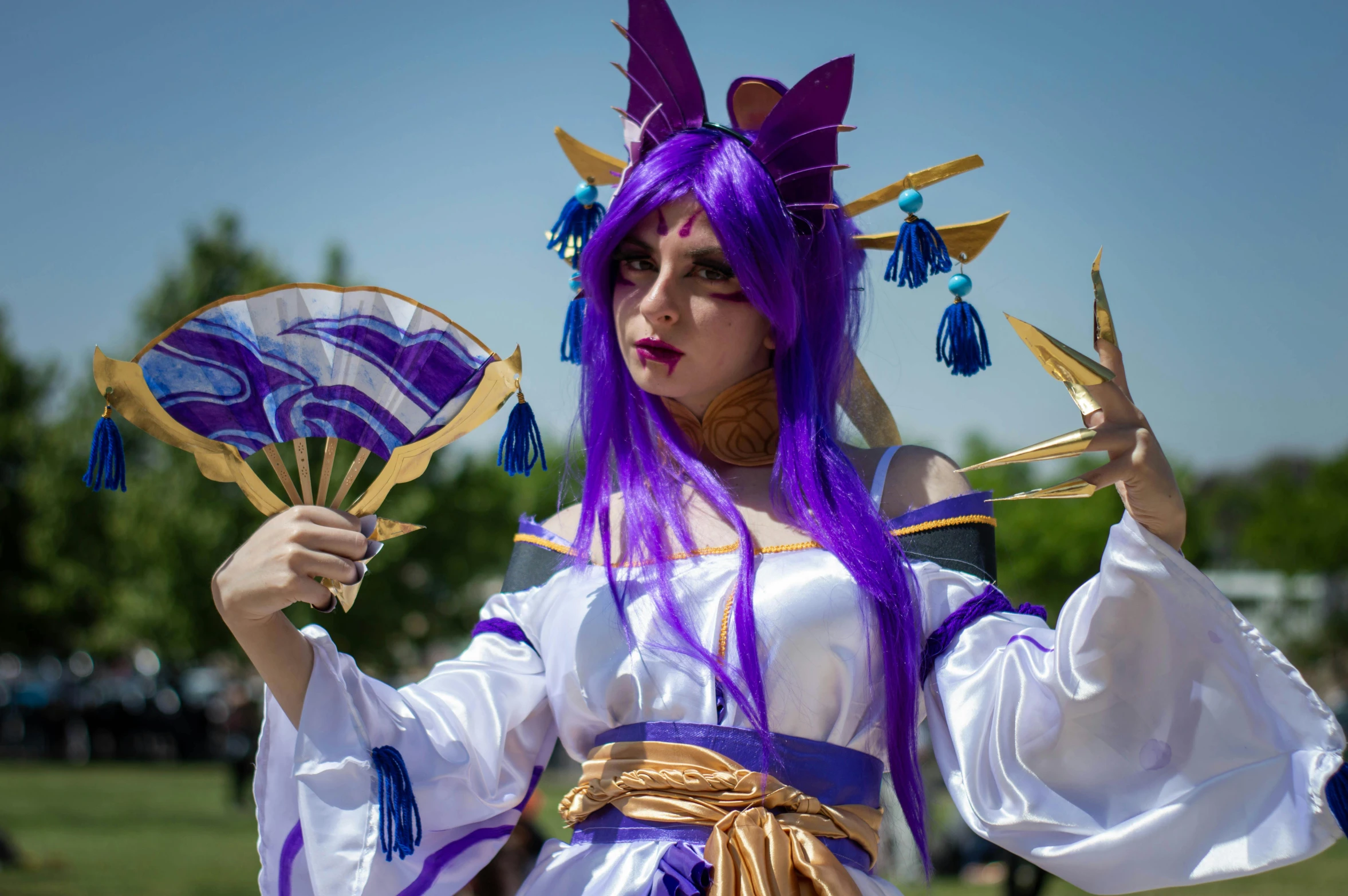 a woman dressed in purple holding two fan like objects