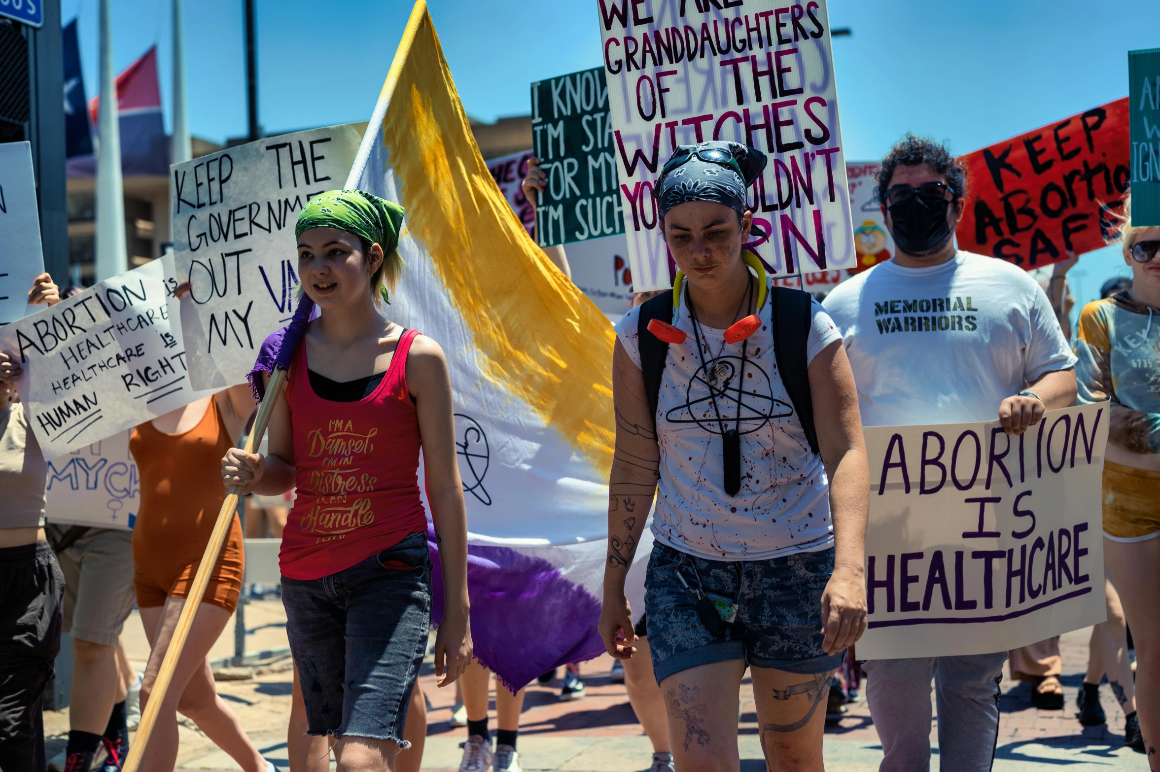 people protesting with signs and flowers on the side