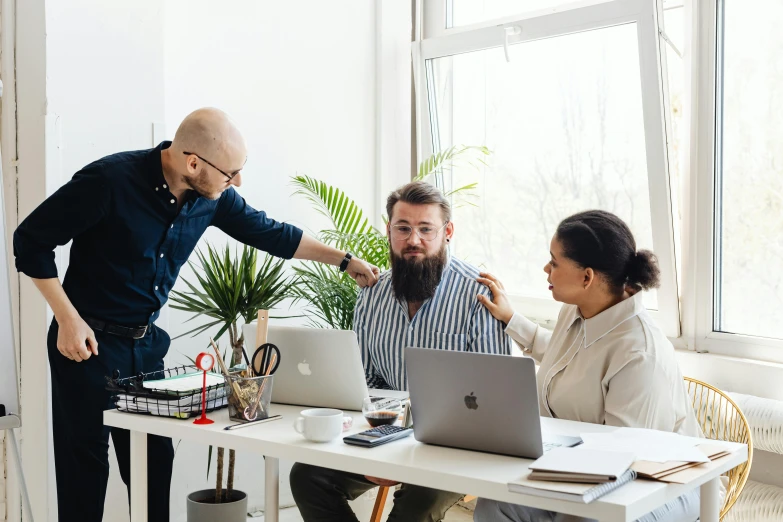 two people using a laptop while standing up in an office