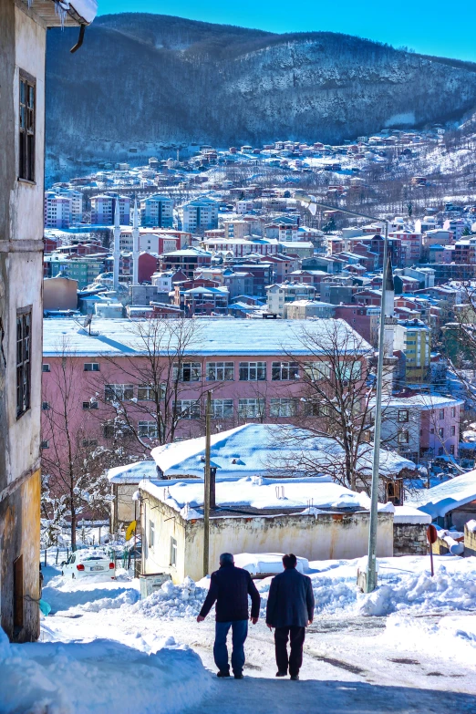 a couple of people walking across a snow covered hill