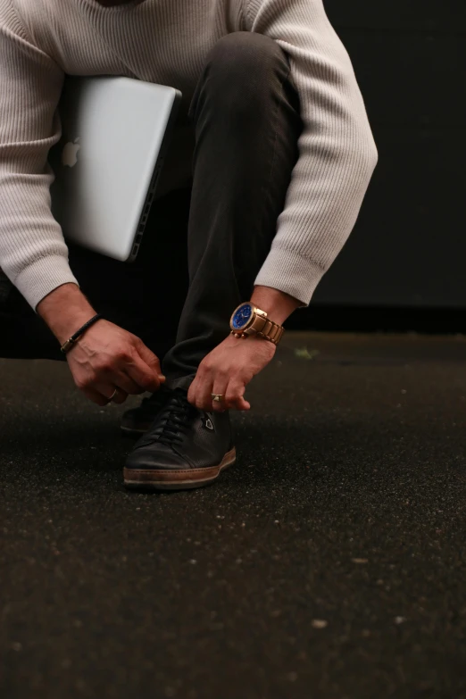 man sitting on his knees putting his shoes up