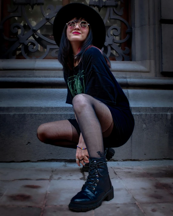 a woman wearing glasses and boots sitting on the ground