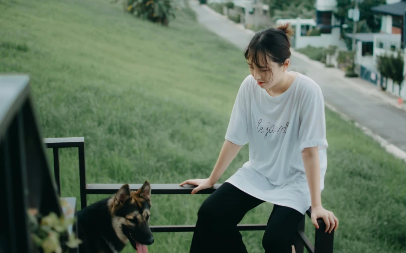 a woman that is sitting on a rail with a dog