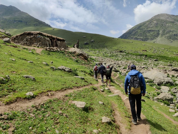 three people on a mountain trail with some animals