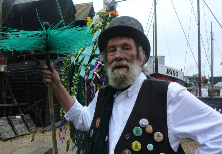 a man dressed in a vest and a hat holds some flowers