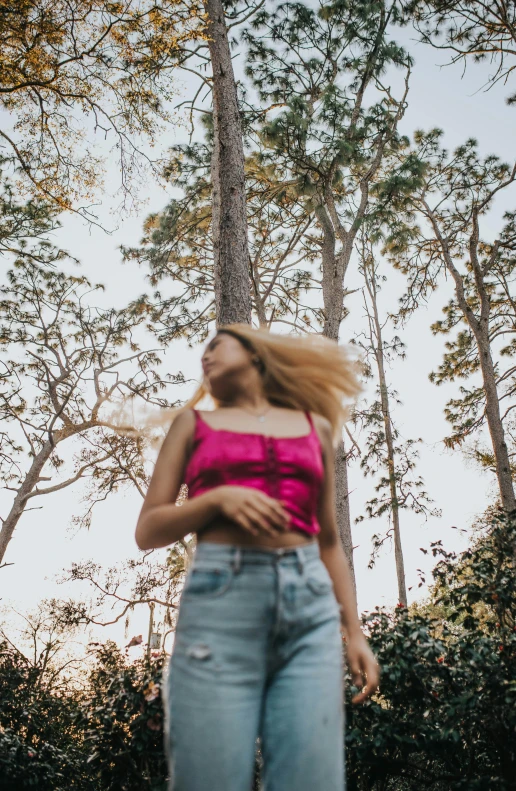 woman in a pink top and blue jeans in the woods