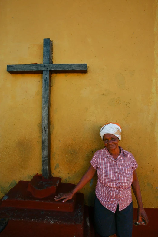 a woman is leaning against a cross on a sidewalk