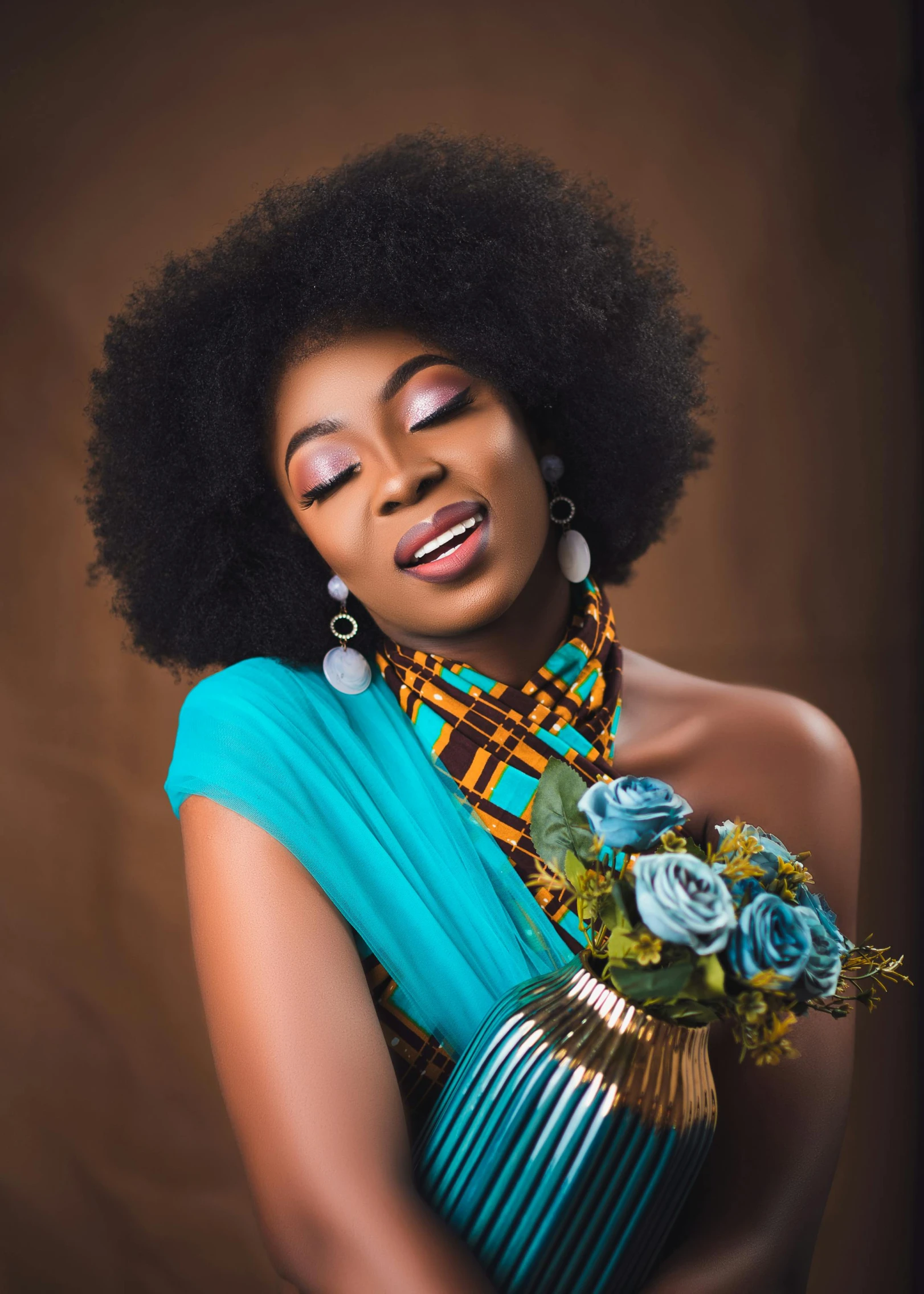 black woman with large earrings holds a vase of flowers