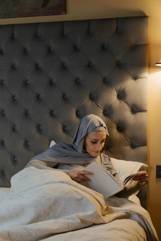 a woman is reading a book while on the bed