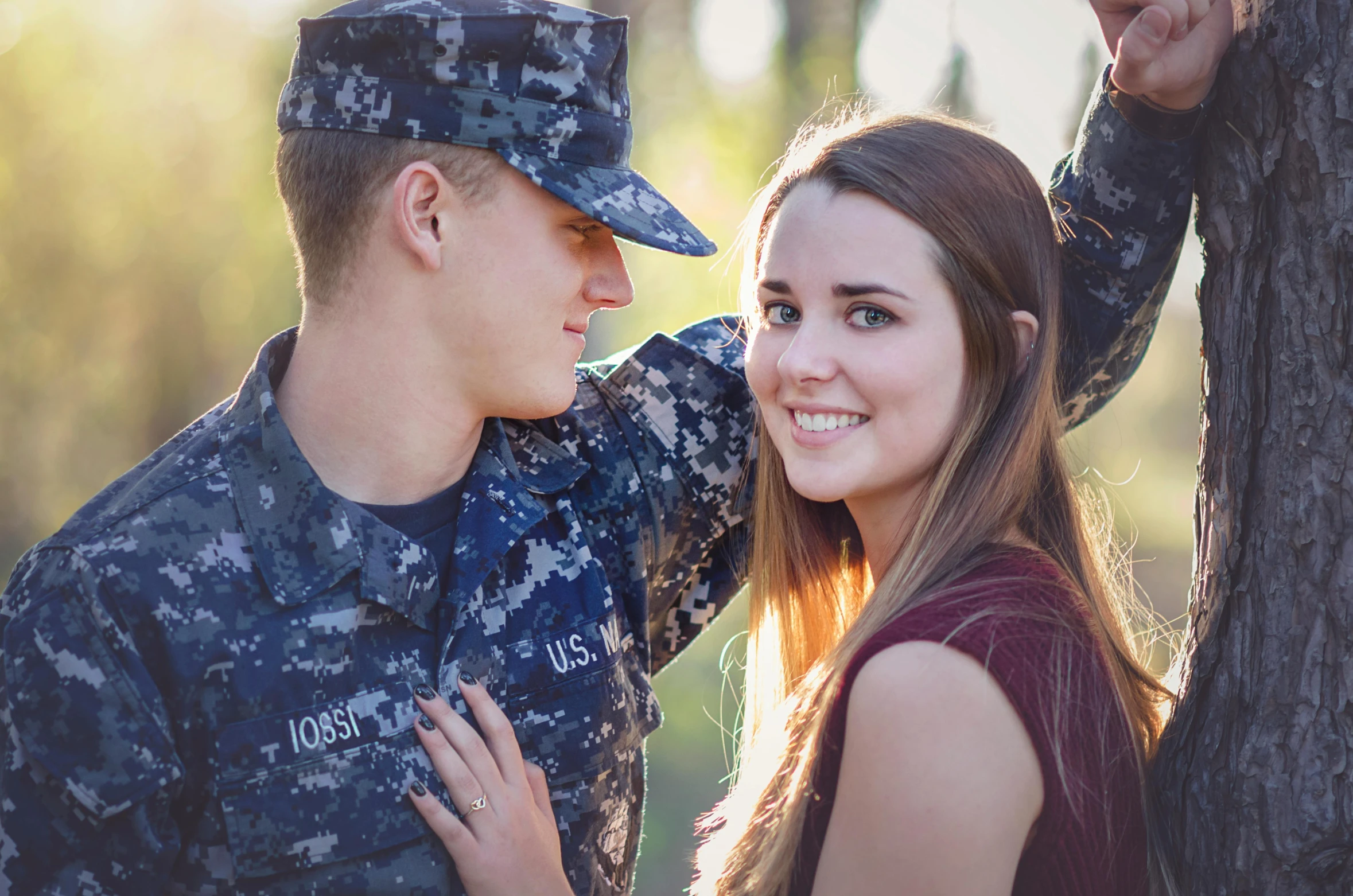 a man and woman standing by a tree hugging