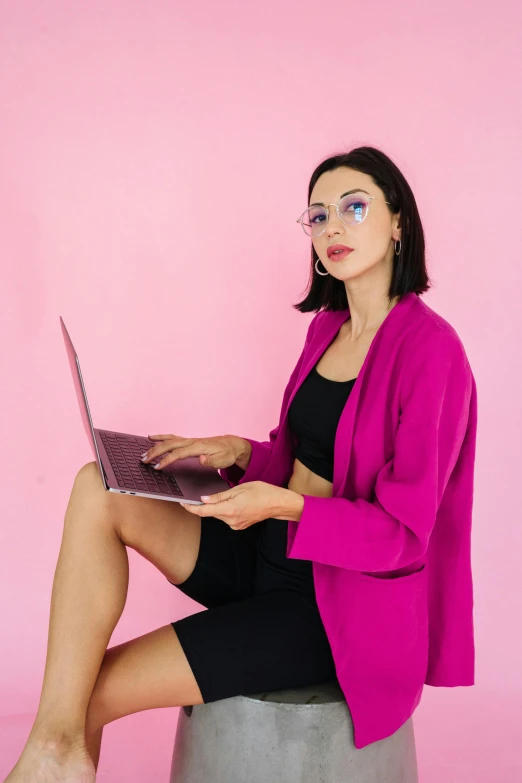 a woman in a pink jacket with a laptop