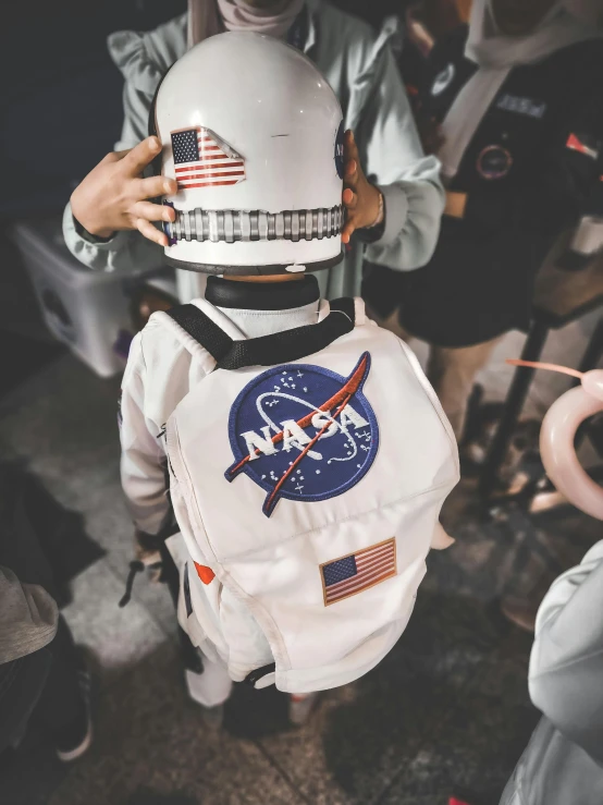 a person in an astronaut outfit holding an american flag