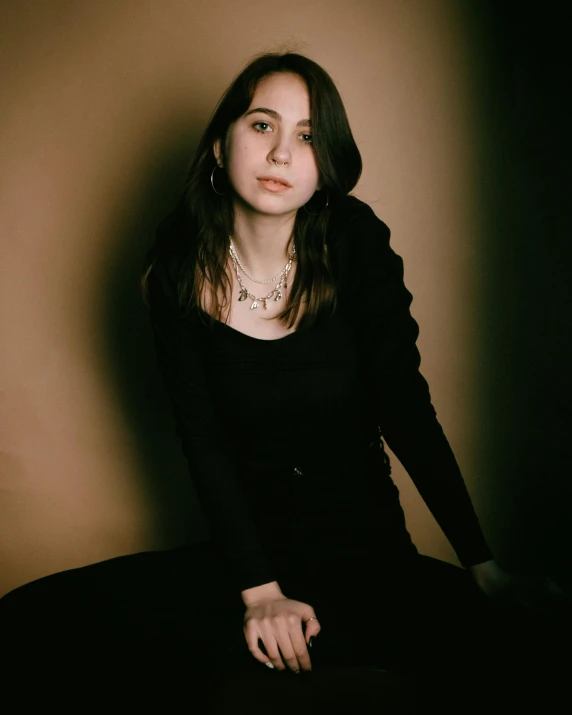 an attractive young woman sitting down against a wall