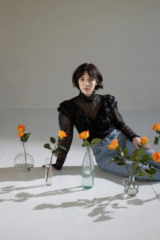 a girl kneeling down and arranging roses in clear vases