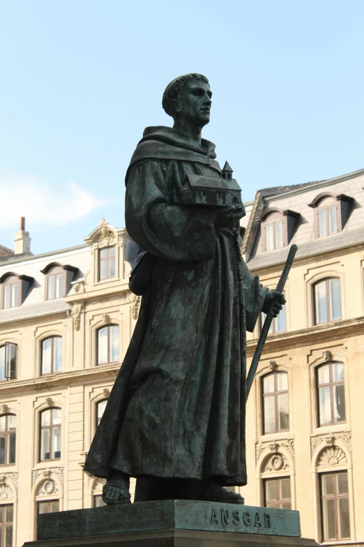 statue of a saint holding a staff outside of a building