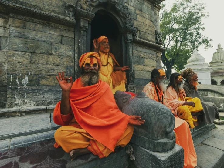 several indian men sitting in the stairs outside a temple