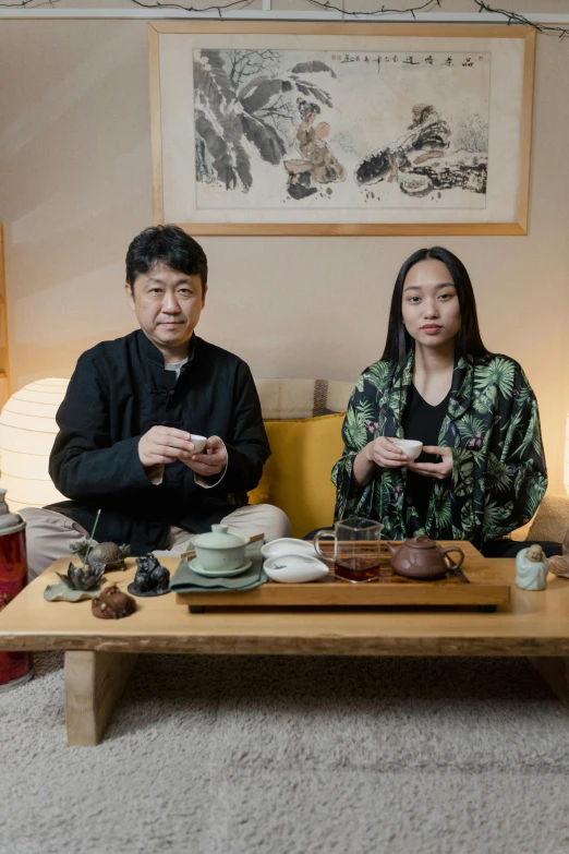 two asian people eating at a table in the middle of living room