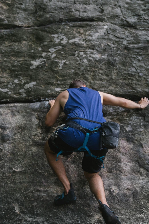 man climbing up on a rocky area and leaning against the edge