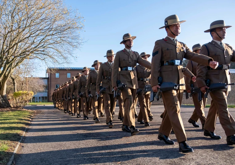 the men in the uniform are marching down the street