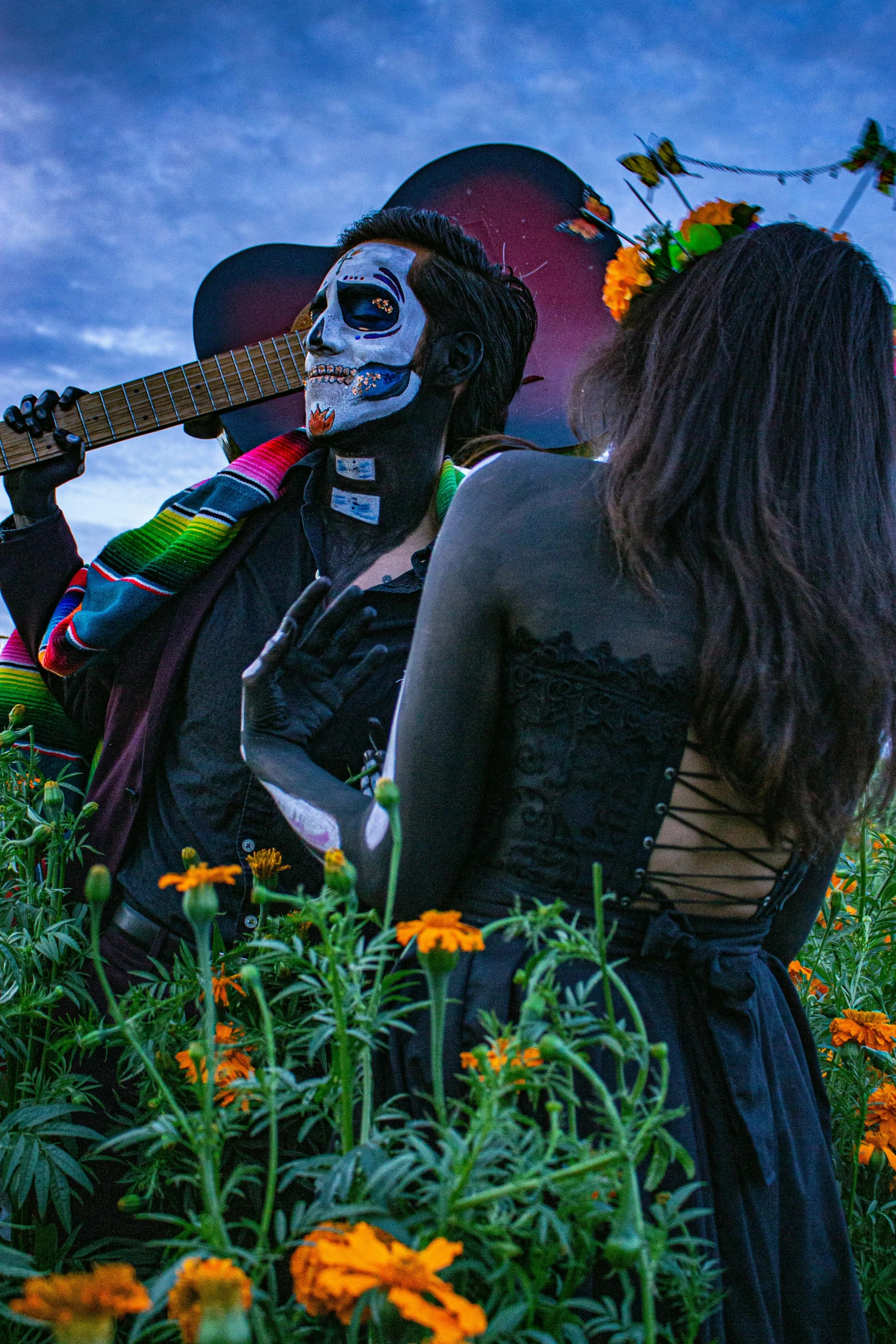 a couple in skeleton makeup standing in some flowers