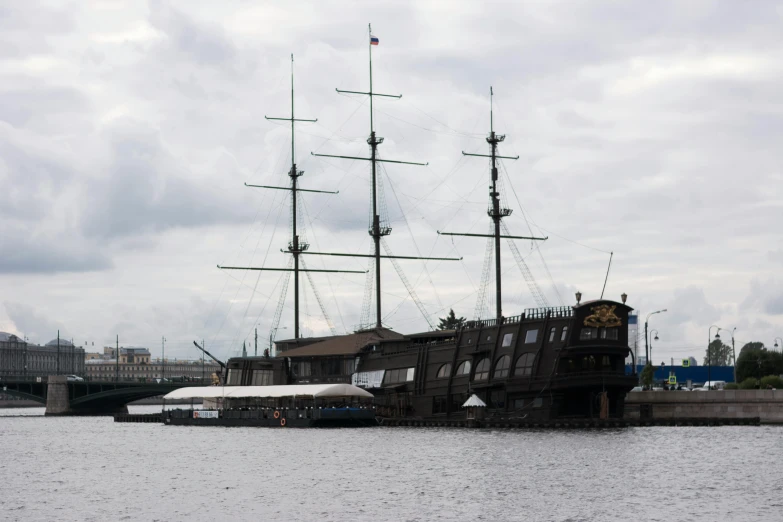 a small ship in the water near some bridge