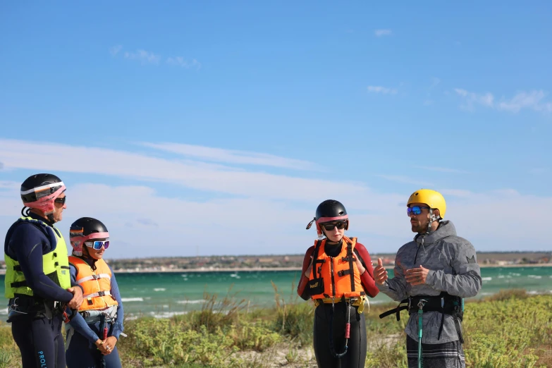 some people with life jackets are standing near the water