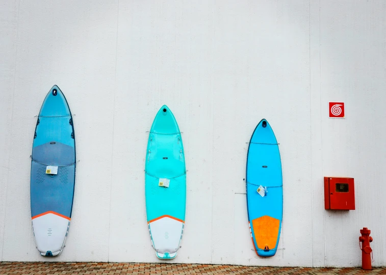 four surfboards are lined up in front of a white wall