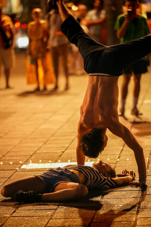 a man in a black suit doing a hand stand on the ground