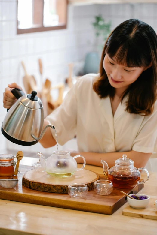 an asian woman pours tea from a teapot