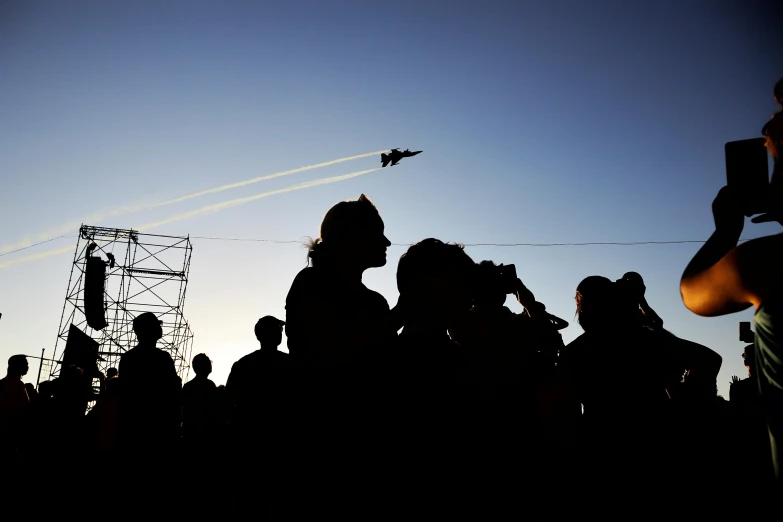 a crowd looking at an airplane flying in the sky