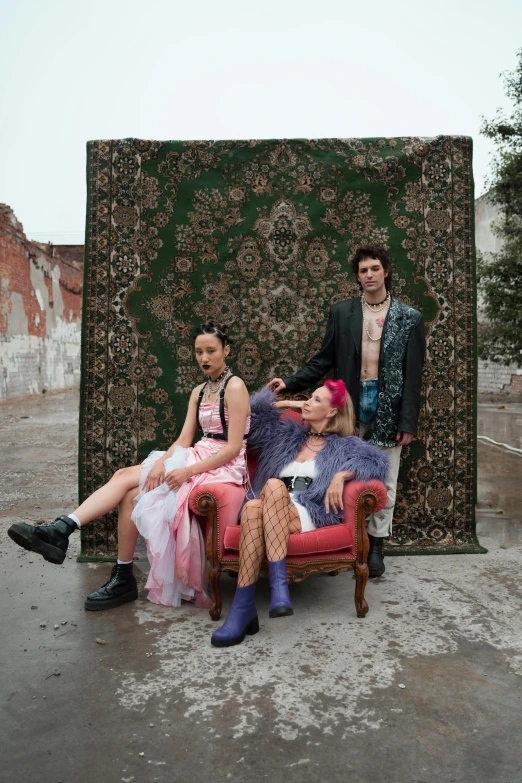 a man in a suit and three women sitting on a pink chair