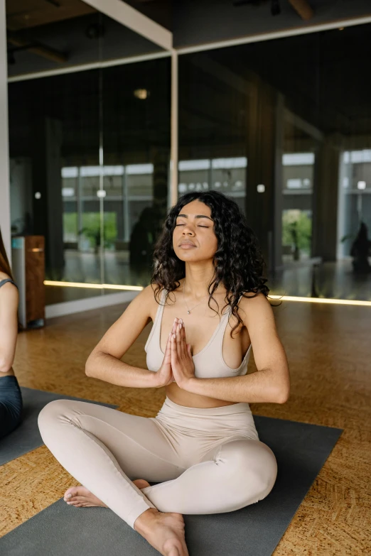 a woman in grey sitting in yoga position with other people looking on