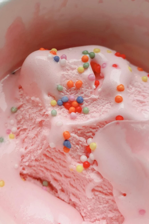 a scoop of pink ice cream with sprinkles in a bowl