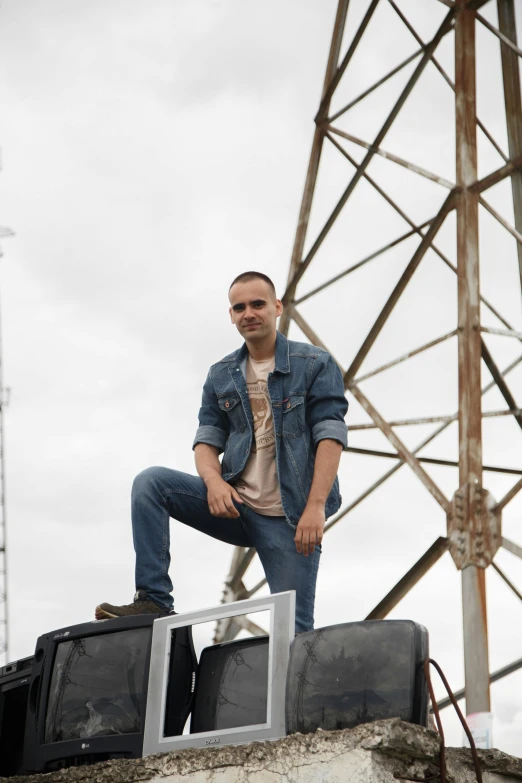 man in jacket standing on ledge beside old television equipment